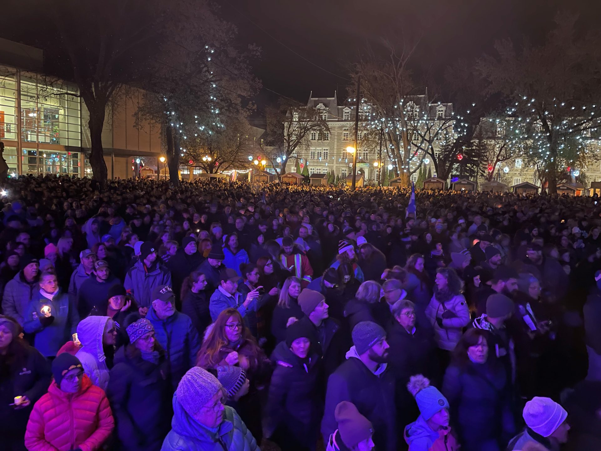 Une foule de milliers de personnes se recueuille dans un parc un soir d'automne.